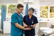 © Austockphoto - Man and woman health care workers  standing next to each other looking at a tablet in the clinic