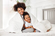 © JenkoAtaman - Happy ethnic family. African american mother and daughter play and laugh in bed.