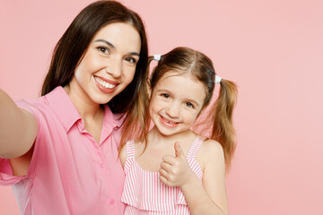 Wall Mural - Close up happy woman wear casual clothes with child kid girl 6-7 years old. Mother daughter do selfie shot pov on mobile cell phone isolated on plain pastel pink background. Family parent day concept.