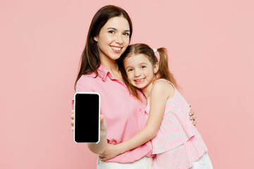Wall Mural - Happy woman wear casual clothes with child kid girl 6-7 years old. Mother daughter holding use blank screen workspace area mobile cell phone isolated on plain pink background Family parent day concept