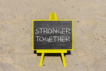Wall Mural - Stronger together symbol. Concept words Stronger together on black chalk blackboard on a beautiful sand beach background. Business, motivational and stronger together concept.