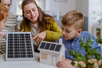 Wall Mural - Young teacher with solar panel learning pupils about solar energy.