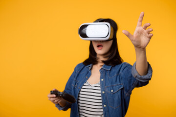 Poster - Young asian woman happy success wearing virtual reality headset game entertainment and holding joystick controller isolated on yellow background. Winner of cyber future video game concept.