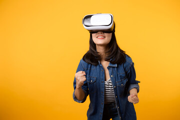 Poster - Young asian woman happy success wearing virtual reality headset game entertainment isolated on yellow background. Winner of cyber future video game concept.