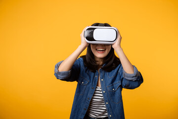 Poster - Young asian woman happy success wearing virtual reality headset game entertainment isolated on yellow background. Winner of cyber future video game concept.