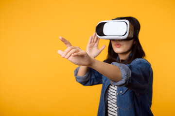 Poster - Young asian woman get experienced wearing virtual reality headset game entertainment isolated on yellow background. Winner of cyber future video game concept.