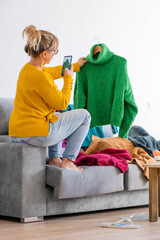 Wall Mural - blonde woman taking photos of clothes to sell through used clothing application from her home
