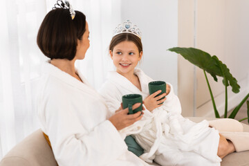 Wall Mural - Girl And Her Mother Wearing Bathrobes And Crowns Drinking Cocoa At Home