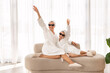 © Prostock-studio - Cool Girls. Cheerful Young Mother And Little Daughter In Bathrobes And Suglasses