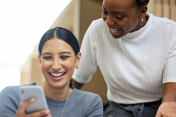 Poster - Check this out. two attractive young businesswomen looking at a cellphone together in the office.