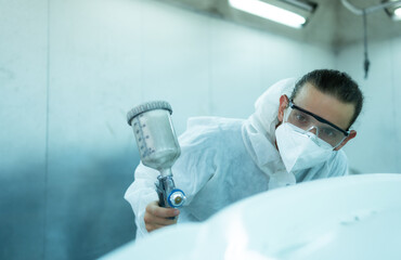 Auto mechanic in car spray room Inspecting the paint sprayed into the front bumper of the car that the pigment is complete, beautiful, harmonious with the original color of the car