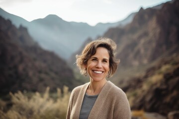 Wall Mural - Portrait of smiling mature woman standing in the middle of the mountains