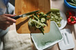 Woman throwing organic food waste in a compost bin. Female person recycling compostable leftovers in a bokashi container