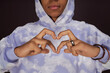 © Seventyfour - Close-up of African American teenage guy in stylish hoodie making heart with his fingers in front of himself while posing in isolation in studio