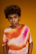 © Seventyfour - Teenage boy in stylish t-shirt with white, pink and orange ombre print standing in front of camera in isolation over yellow background