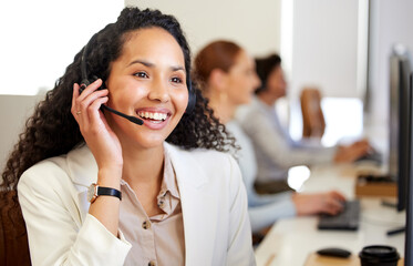 Poster - Well do our best to help you out. a young call centre agent working in an office with her colleagues in the background.