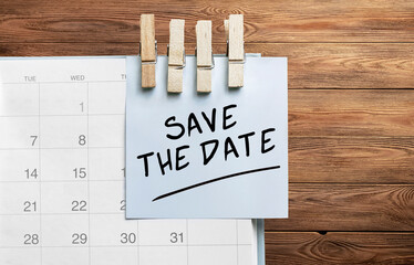 Poster - Blue sticker attached to a calendar on a wooden background with text SAVE THE DATE