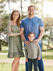 Poster - Young happy caucasian family relaxing and standing together in nature. Loving parents spending time with their little son at the park. Carefree child bonding with mom and dad