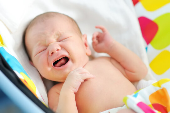Close-up portrait of sweet newborn baby. Crying baby infant during colic.