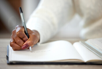 Poster - I get every goal I go after. an unrecognisable woman making notes in a book while studying at home.
