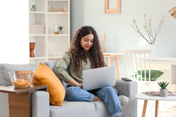 Sticker - Teenage girl using laptop on sofa at home