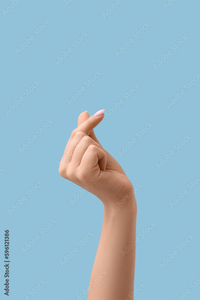 Woman making heart with her fingers on blue background