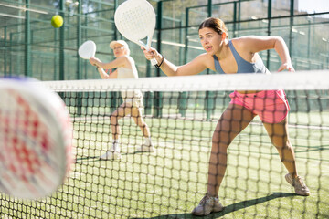 Wall Mural - Determined sporty young woman doing her best playing padel in court