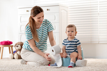 mother training her child to sit on baby potty indoors
