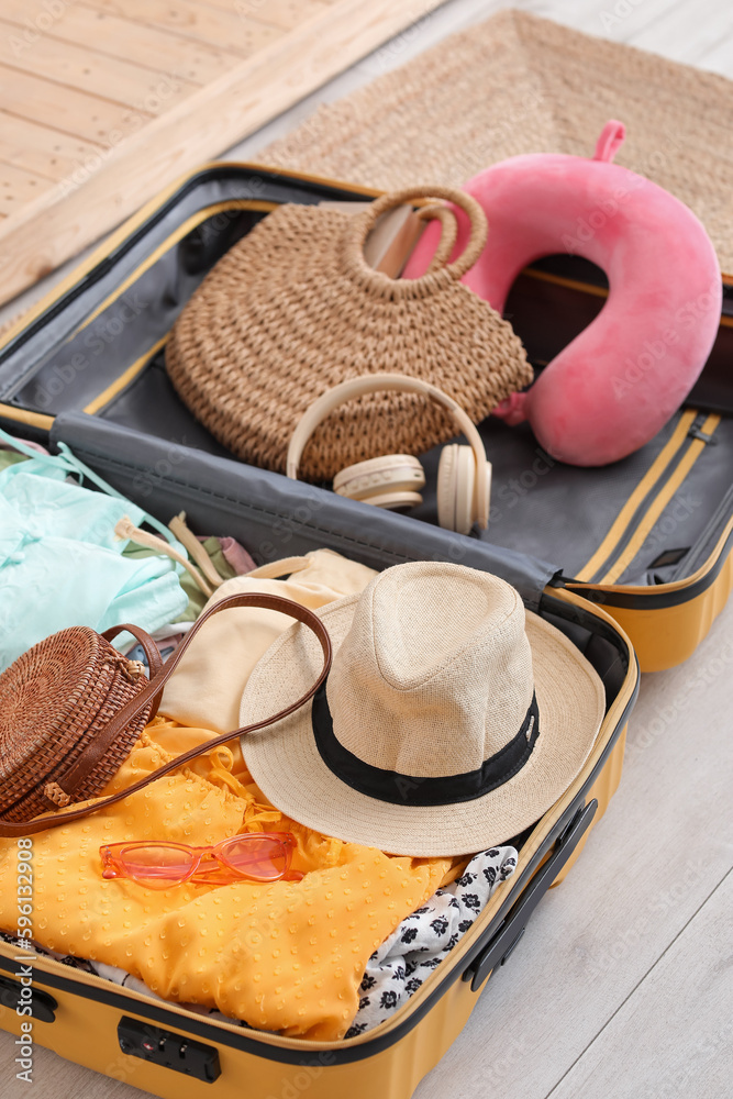 Open suitcase with beach accessories on floor in bedroom