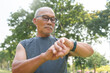 © eggeeggjiew - Sporty Asian senior man checking his smartwatch for training running at nature park outdoor. Mature Adult male checking pulse after jogging. Fitness tracker