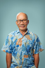 Wall Mural - Portrait of Happy Asian Chinese senior man wearing casual T-shirt and eyeglasses smiling looking at camera over blue isolated background indoors.