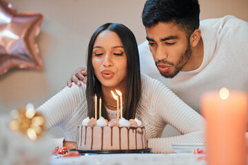 Poster - Lets make a wish before we cut the cake. a young couple blowing candles on a cake while celebrating a birthday at home.