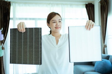 Asian woman changing the dirty air purifier filter after using for a long time in the dirty air environment. Using air purifier clean the air for better atmosphere in a house.