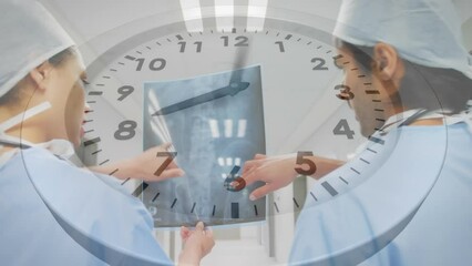 Sticker - Animation of clock over diverse male and female surgeons discussing over x-ray report at hospital