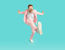 Happy, Funny Man Dancing, Singing, Relaxing And Having Fun. Full Body Length Shot Of Joyful Dancing Young Man Wearing Trendy Pink Party Suit And White Shoes Kicking His Leg Isolated On Blue Background