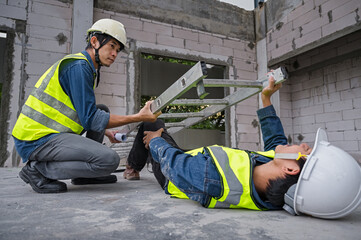 Wall Mural - Accidents at work. Asian engineer fell from a height, fell to the ground and was crushed by a ladder. An engineer colleague rushed to the rescue. Work accident concept, construction site accident.