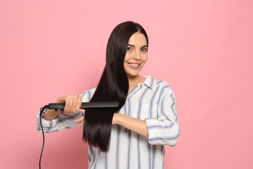 Canvas Print - Beautiful happy woman using hair iron on pink background