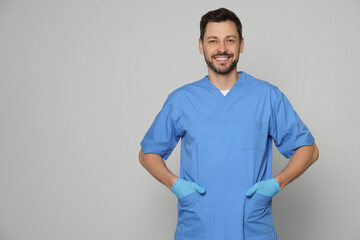 Wall Mural - Doctor or medical assistant (male nurse) in uniform on light grey background. Space for text