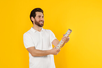 Canvas Print - Happy man with party popper on yellow background. Space for text