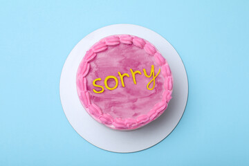 Wall Mural - Apology. Cake with word Sorry of cream on light blue background, top view