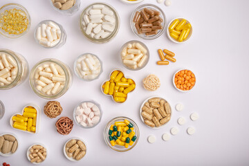Wall Mural - Nutritional supplements, minerals and vitamins in forms of colored pills, tablets and capsules in small jars on hite background from above. A large amount of vitamins.