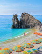 © Chirapriya - Asian women visit a Pebble beach of Monterosso Cinque Terre Italy, Chairs and umbrellas on the beach