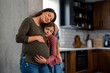 © Dorde - Beautiful happy pregnant single mother and her sweet lovely young daughter snuggling at home, daydreaming about the baby in stomach. Family love and support. Mom with child. Copy space