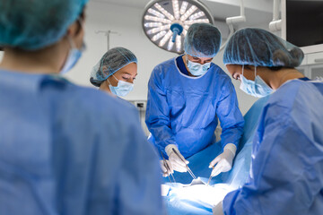 Canvas Print - Team of Professional surgeon, Assistants and Nurses Performing Invasive Surgery on a Patient in the Hospital Operating Room. Surgeons Talk and Use Instruments. Real Modern Hospital.