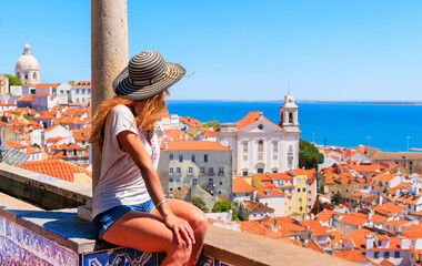 Wall Mural - Woman tourist sitting on balcony looking at panoramic view of rooftop of Lisbon- Portugal