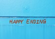 Blue wall with handwriting text HAPPY ENDING - means ending of story or or events in which the people involved are all happy - when all problems are solved
