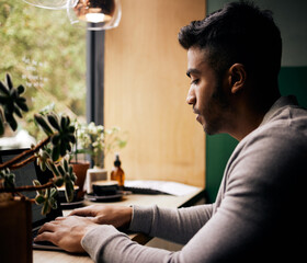 Poster - Young mixed race man or student browsing on a laptop in a cafe. One indian guy studying or working freelance at a restaurant. Typing to do research and planning online for blog, work or assignment