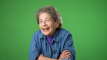 Portrait of happy smiling elderly senior old woman nod head yes, with wrinkled skin and grey hair on green screen background.