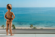 Cute Little Boy Enjoying View From Balcony Of Beachfront Hotel Or Apartment During Summer Vacations