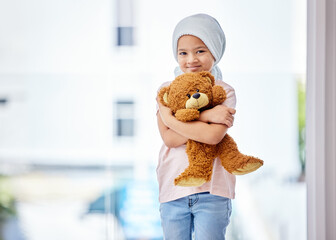 Health is the greatest gift. Shot of a little girl standing with her teddy in a clinic.